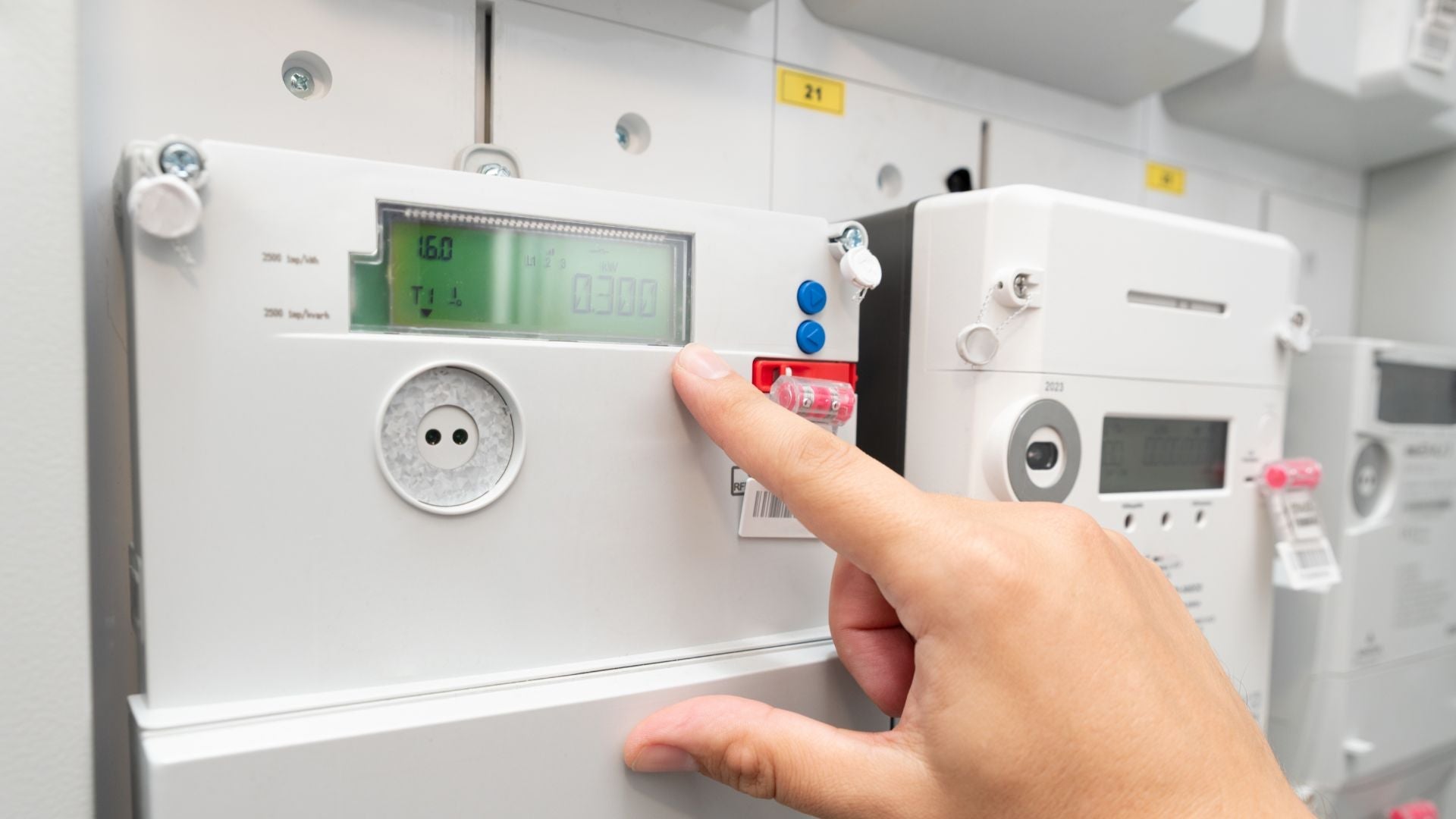 Balkonkraftwerk Speicher Nulleinspeisung Titelbild - Nahaufnahme einer Hand, die auf einen digitalen Stromzähler zeigt, zur Überprüfung des Stromverbrauchs
