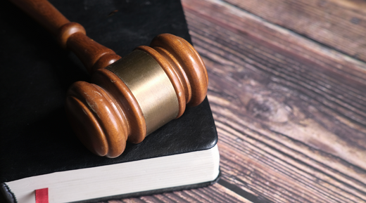 Balkonkraftwerk Rechtslage Titelbild. Zu sehen ist eine Detailaufnahme eines Holztisches, auf diesem liegt ein Buch und ein Richterhammer obendrauf.