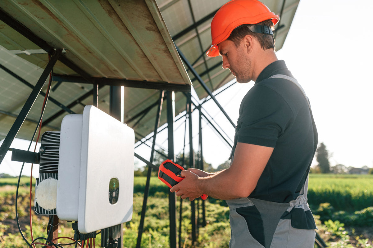 Was ist ein Wechselrichter Titelbild. Ein Techniker überprüft einen Wechselrichter einer Solaranlage mit einem Messgerät, um die Leistung und Funktion der Anlage sicherzustellen.